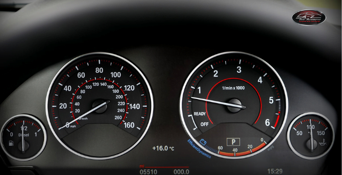 Close-up of a car's dashboard, showing the speedometer, tachometer, fuel gauge, and digital temperature and time displays. Perfect detail for anyone interested in automotive repair or visiting an auto shop.