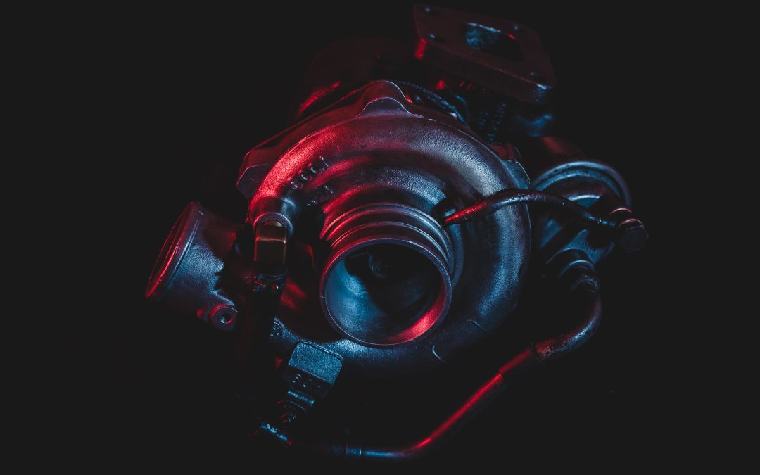 A close-up of an automotive turbocharger against a dark background, illuminated with red and blue lights, evokes the precision you can expect from any top-tier auto body shop.