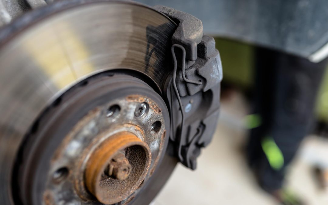 Close-up of a car's disc brake system, showing rust on the rotor surface.