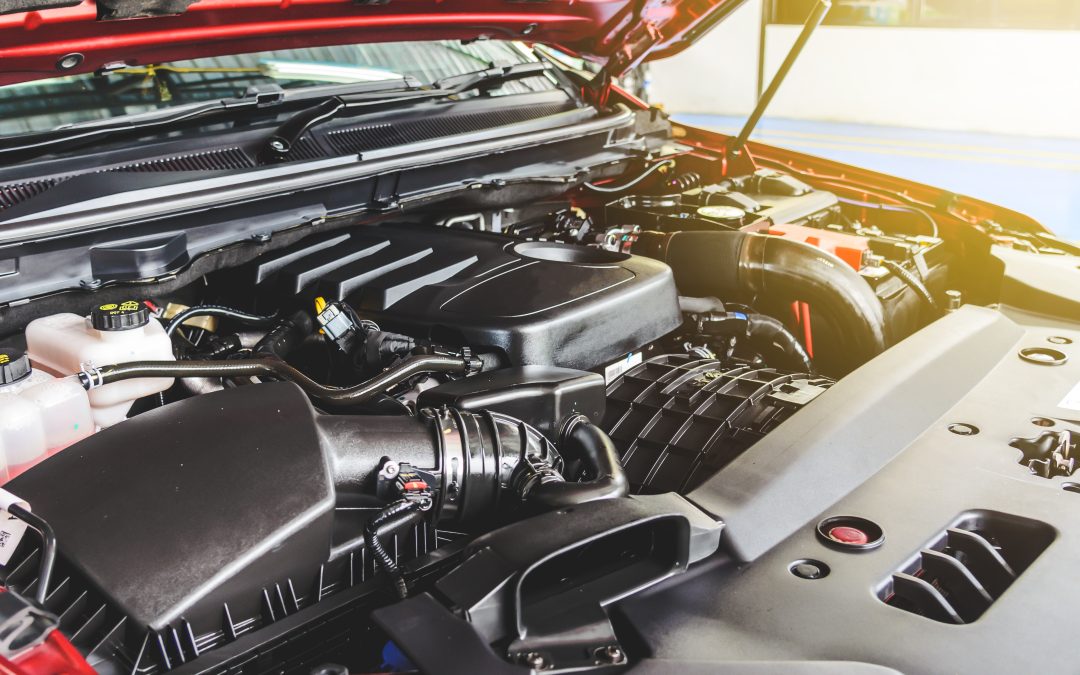 Car engine under the open hood, displaying various components and parts in a well-lit environment.